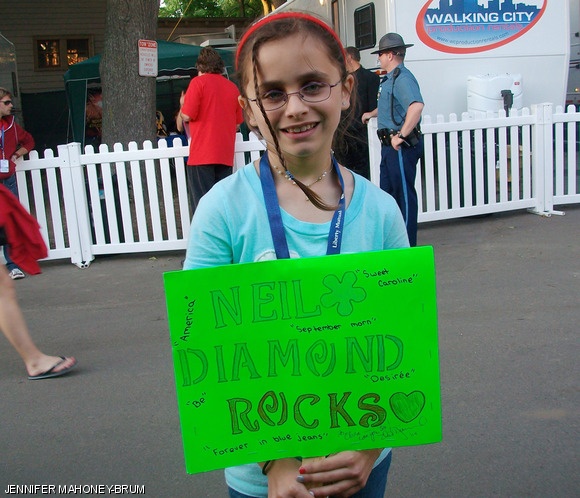 Olivia M. Brum from Lowell, MA, holding her autographed sign, welcomes Neil Diamond.