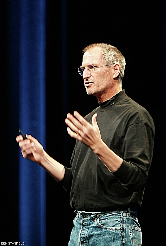 Steve Jobs, in his characteristic blue jeans and black turtleneck, gives one of his famous keynote addresses.