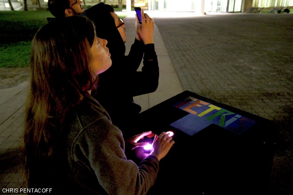 A woman plays Tetris on the display on the Green Building during Campus Preview Weekend.