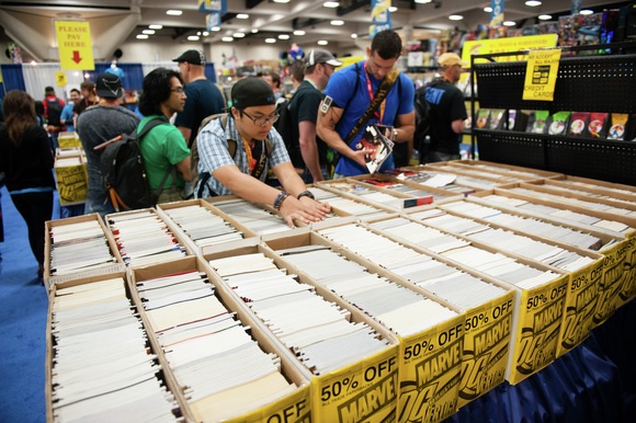 Comic-Con attendees rifle through discounted comics on the expo floor.