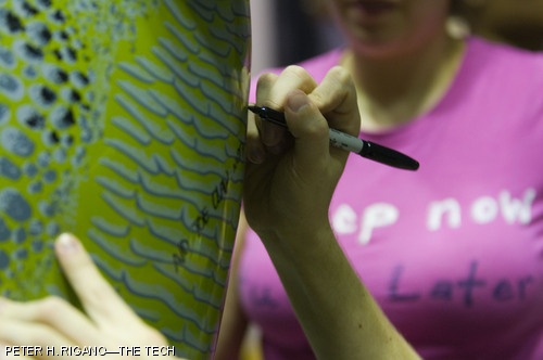 xkcd creator Randall Munroe autographs an inflatable dinosaur while explaining why it is technically not a velociraptor.