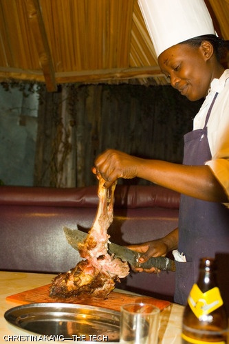 A cook chops goat meat with a machete in an outdoor booth in Nairobi, Kenya.