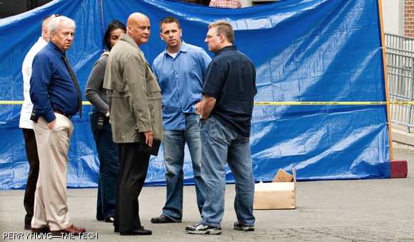 Emergency personnel, including MIT Police Captain Albert F. Pierce Jr. (center, facing right), investigate the death of Han Nguyen G, who was found in the parking lot on the east side of Building E19 on Tuesday, June 2.