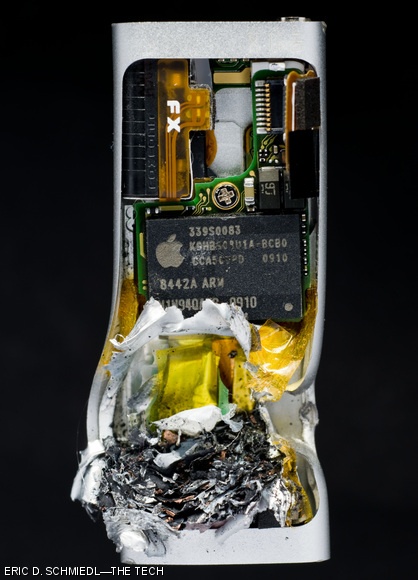 The busted iPod Shuffle is seen after its encounter with a .22 bullet. The ash seen in the lower part of the unit where the bullet struck is the Lithium battery.