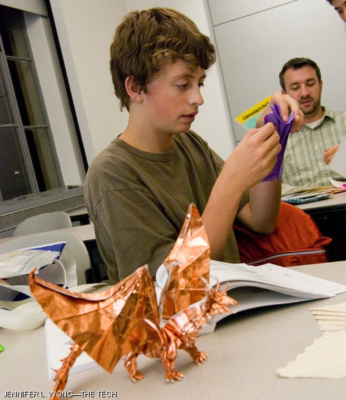Jared Walz works on a model of a “chambered nautilus shell” with his “ancient dragon” in the foreground during a meeting of OrigaMIT, a campus origami group.