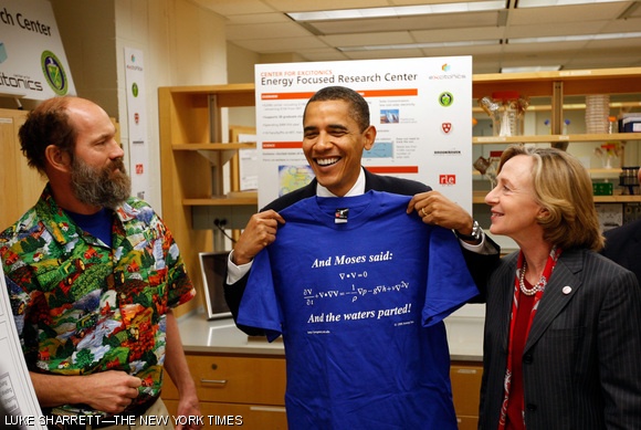 President Barack Obama shows off his newly acquired T-shirt after learning about the energy storage research conducted by Professor Alexander H. Slocum ’82. MIT President Susan Hockfield accompanied Obama during his tour through the labs at MIT on Friday. Slocum explained a system for harnessing excess wind energy. When the wind is not blowing, water flowing into the storage area through a turbine produces electricity. When the wind is blowing, excess power is used to pump water out of the storage area.