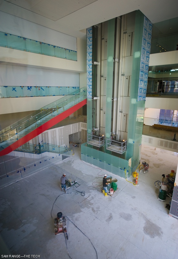 Workers begin grinding the marble chunk-infused floor of the Media Lab extension’s central atrium, which will be polished to a glossy finish. The expanse of interconnected airspaces surrounding the atrium necessitated smoke curtains (left) for emergency air evacuation, shown here closed for testing.