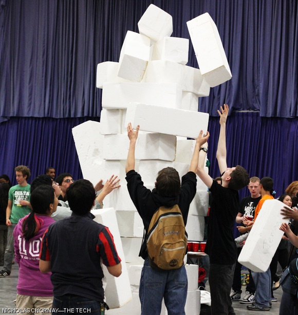 Prefrosh attempt to rebuild a giant foam Jenga tower, but to no avail.