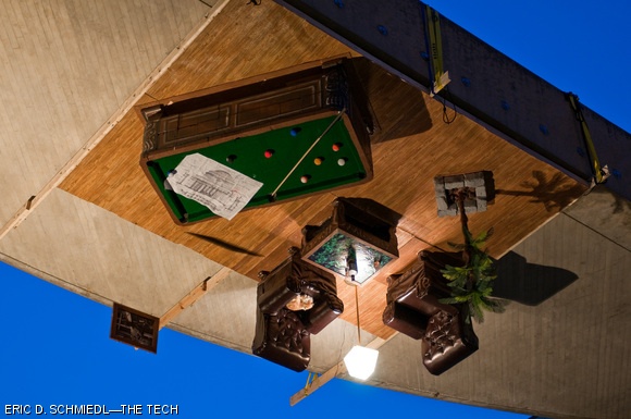 For Campus Preview Weekend 2010, hackers installed a high-class lounge (complete with pool table, sleeping cat, whiskey, and hack plans) upside down on the Media Lab Arch on Thursday morning.