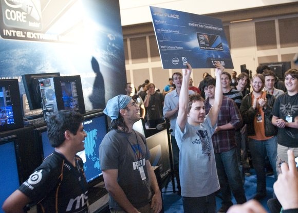 TOP STARCRAFT 2 PLAYER CHRIS “HUK” LORANGER PROUDLY HOLDS UP HIS THIRD PLACE CHECK FOR THE INTEL EXTREME MASTERS AMERICAN CHAMPIONSHIP FINALS TOURNAMENT. TO HIS LEFT STAND FIRST PLACE JIAN CARLO JOAN MORAYRA “FENIX” ALEJO (FAR LEFT) AND SECOND PLACE KEVIN “QXC” RILEY (NEAR LEFT).