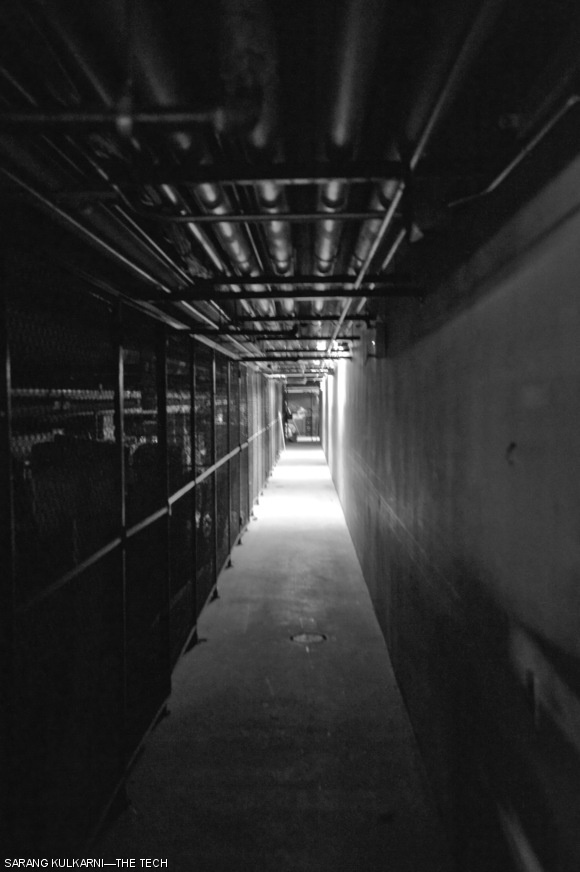 Dark hallways like this one shed new light on the phrase “light at the end of the tunnel.” This particular hallway located in the basement of Building 10 is noteworthy for this effect because of the relatively low height of its ceiling, small effective width from the presence of storage cages, and bright lights at its far end.
The Infinite Corridor is occasionally closed for floor waxing at night; a way to get across campus at such times without leaving the warmth of MIT’s indoors is to go down one floor and use the basement.