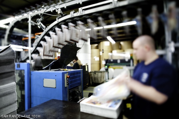 A machine adds inserts to the inside of complete, folded papers.