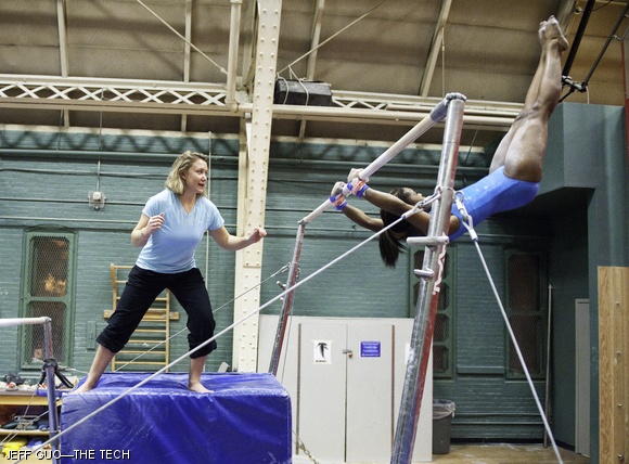 Karis E. Stevenson ’11 is coached on the uneven bars.