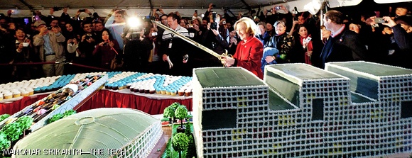 MIT President Susan J. Hockfield uses a sword to cut the MIT-shaped cake.