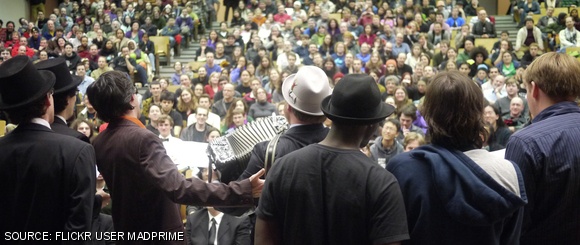 Participants gather at the Mystery Hunt Wrap-Up in 26-100 on Sunday evening. The Hunt ended when the coin was found in little Kresge at 10:27 p.m. on Saturday. Onstage, from left to right: Josh Ain, C. Scott Ananian, Francis Heaney, Patrick Blindauer, Xavier C. Jackson ’12, Kevin Carde, and Barack Michener.