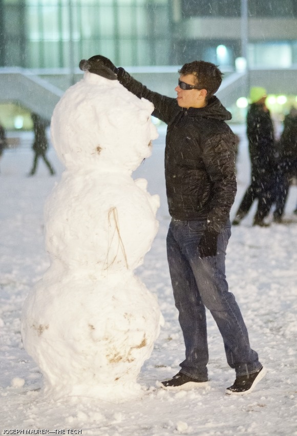 Bruno B. F. Faviero ’15, a Tech staffer, tops a newly constructed snowman with a hat on Monday evening in front of the Student Center. Light snowfall blanketed Cambridge on Monday evening.