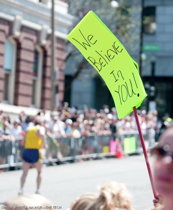 Runners are encouraged by supportive signs from the crowd.