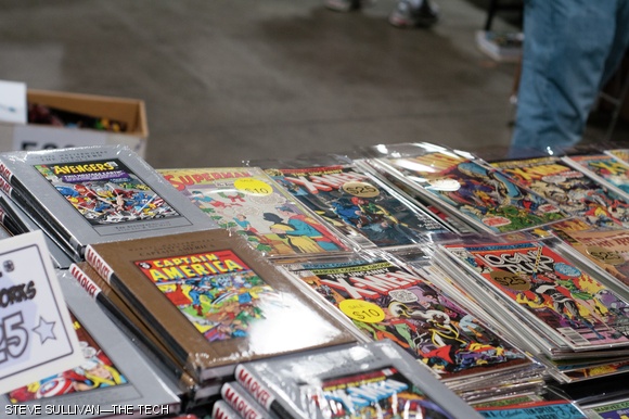 Stacks of comics litter the tables of a merchant’s booth.