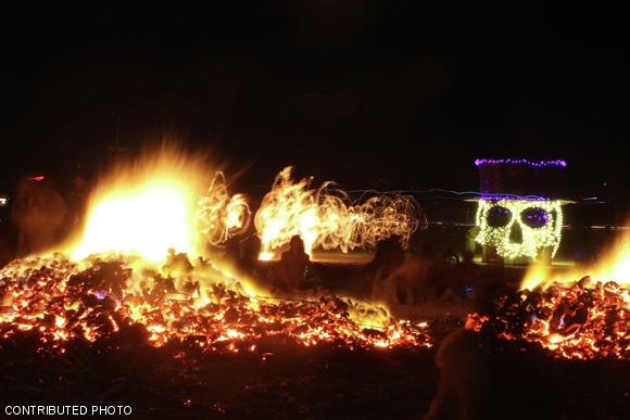 Christopher Varenhorst ‘09 sits by the embers of the Circle of Regional Effigies (CORE). The Man is surrounded by a ring of 34 wooden effigies, each built by a different regional Burning Man group and burned simultaneously on Thursday.