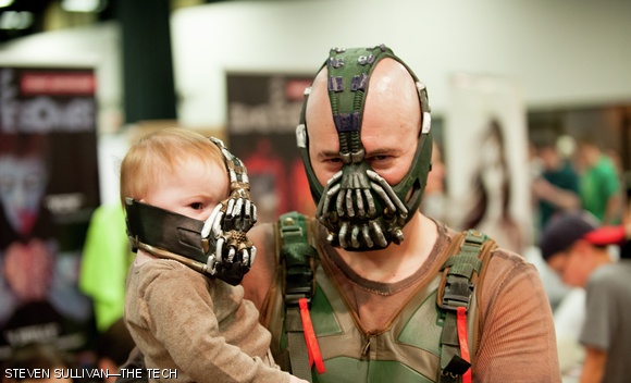 A Bane cosplayer walks the halls of Comic Con with his protege, Baby-Bane.