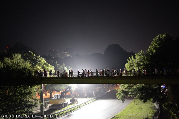 Thousands of fireworks attendees stream across the footbridge overlooking Storrow Drive, making their way from the Hatch Shell and Esplanade back into Boston.