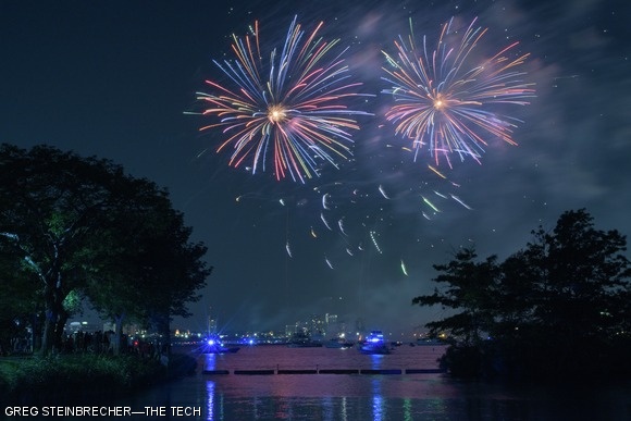 As seen from the bank of the Esplanade near the Hatch Shell, fireworks explode over the Charles River.