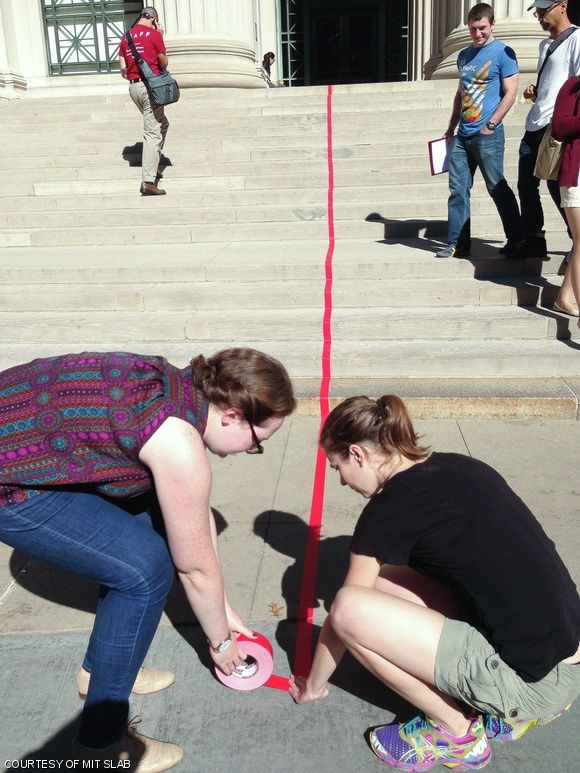 From left to right, Elizabeth L. Resor ’13 and Alexis B. Howland ’13 ran red tape through campus to the Wolk Gallery for the opening of Sidewalk City last week. The exhibit explores Vietnamese sidewalk life and street vending through a map.