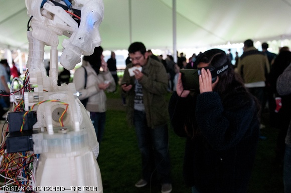 A vistor at MIT’s Mini Maker Faire uses an Oculus Rift virtual reality headset to interfact with an InMoov robot.