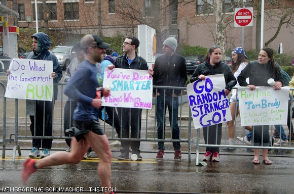 A large crowd gathered near Boston College to cheer runners on, holding witty encouraging signs.