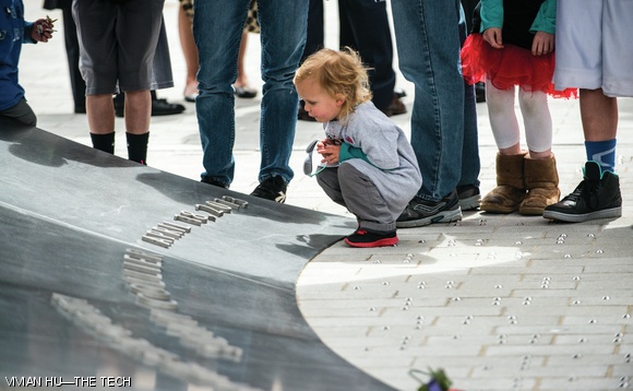 Sean Collier’s 2-year-old cousin crouches by the new memorial following Wednesday’s dedication. The ceremony was attended by hundreds of people, including students, MIT President L. Rafael Reif, and police officers from nearby towns.